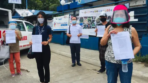 Karapatan Activists on 'wanted' poster holding up the police reports they filed