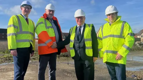 Essex County Council Four men wearing Hi-Vis jackets and helmets while standing on a construction site