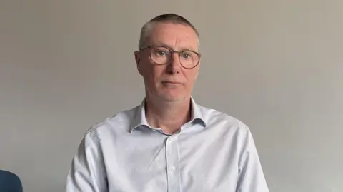 Anthony May, Chief Executive Officer of Nottingham University Hospitals Nu NHS Trust, wearing a white shirt