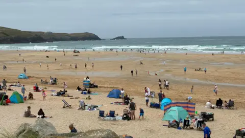 BBC A wide sandy beach with lots of people on, and in the sea