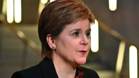 Getty Images Nicola Sturgeon, with brown hair, wearing a dark jacket, looks to her left in a close-up shot in the Scottish Parliament 