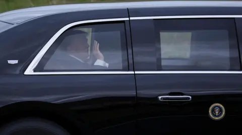 Reuters President Donald Trump waves from inside a black vehicle on his way to Turnberry