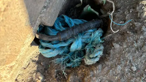 Vanessa Alderton A rigid cable in a hole next to a wall is bound with black insulation tape.