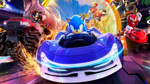 A captura de tela Sega A mostra Sonic the Hedgehog, dirigindo um carro azul esportivo, com uma variedade de outros personagens da série em veículos atrás dele. 