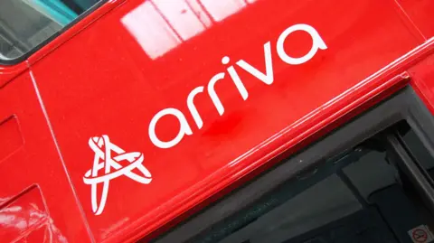 A close up of the red Arriva logo on a red bus.