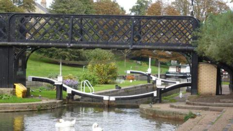River Cam at Jesus Green, showing closed lock gates, spanned by a footbridge, and two swans in the water 