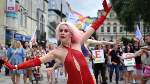 Woman dressed in red taking part in Pride Cymru parade