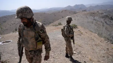 Pakistani soldiers patrol next to a newly fenced border fencing along Afghan border at Kitton Orchard Post in Pakistan's North Waziristan on 18 October 2017.