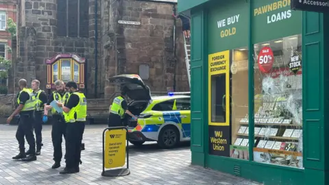 Police near smashed windows of Ramsdens Pawnbrokers