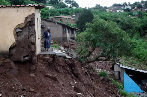Rogan Ward / Reuters A woman surveys flood damage outside her home in KwaNdengezi, Durban