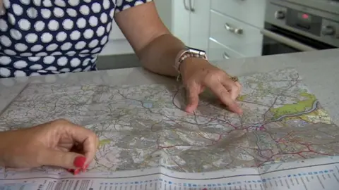 A woman points to an area on a paper map on a table