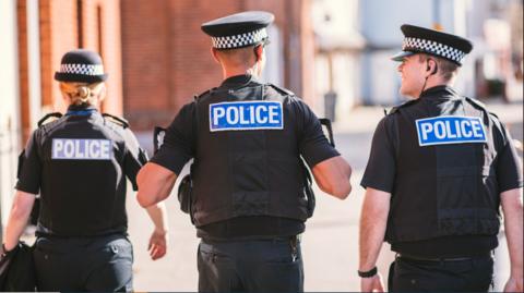 three police officers walking away from the camera 