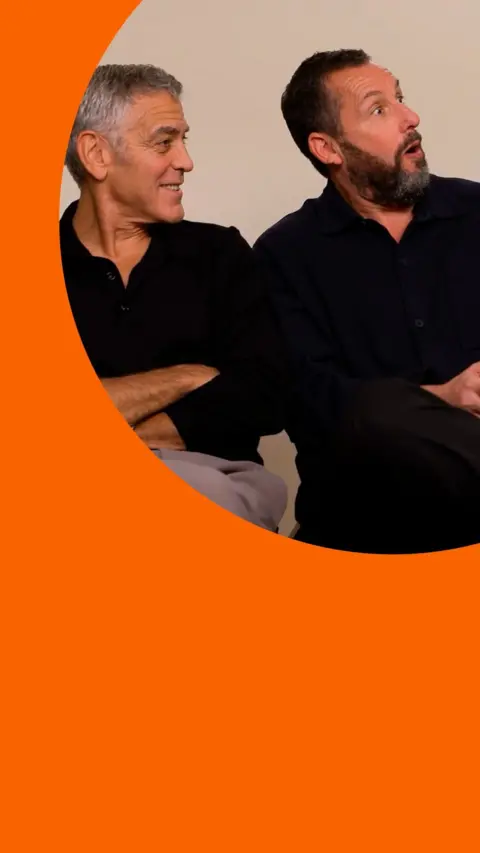 George Clooney and Adam Sandler, both in black shirts, look to the side. Adam looks shocked