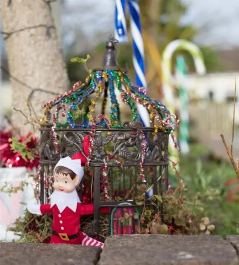 James Murray Elf with bird cage house and blue candy cane