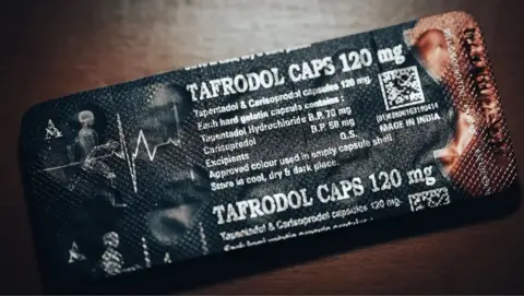 BBC back side of a package - this is black "Tafrodol caps 120 mg" Written in white and has an image that looks like a body x-ray.