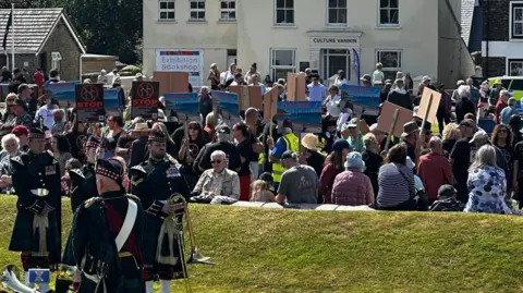 Protesters with placards among those watching the ceremony.