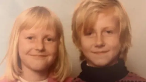 Steve Damon Steve Damon is pictured as a child sitting beside his sister in what looks like a school photograph from the 1970s. Both Steve and his sister have blonde hair. Steve is wearing a polo neck jumper and his sister is wearing a cream top with a pink cardigan over it. Both are smiling though Steve's smile looks a little sad.