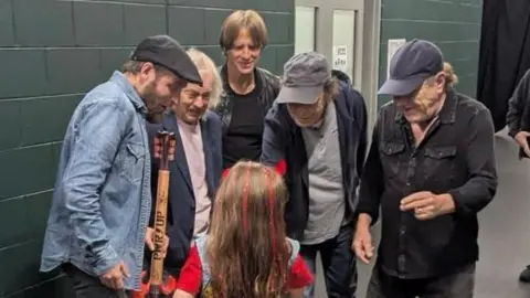 Ben Hodgart/Big Energy Productions A wide shot of Rob and his daughter with band members from AC/DC, all smiling