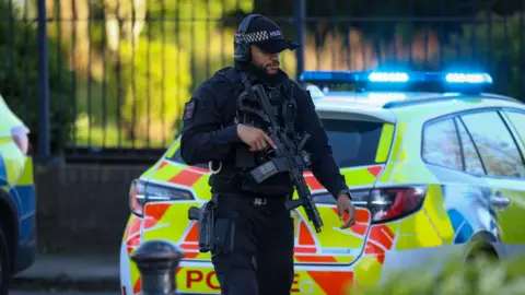 ASP Police officer holding gun next to police car 