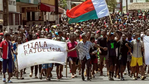 AFP a través de fotos de una mierda frente a pancartas que dicen 'Raughmine Back' en los Malagas. También se puede ver la bandera madagascánica. 