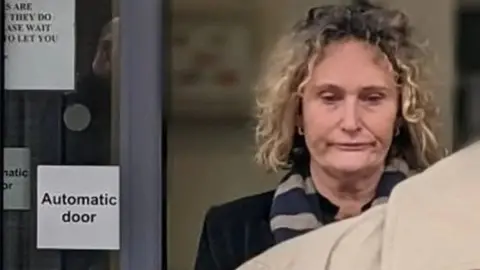 BBC A blonde woman with curly hair walking out of Chelmsford Crown Court. It is a zoomed in image of her face and she appears to be wearing a black outfit with a scarf