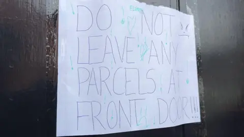 A sign on the glass of a front door that says in capital letters: "Do not leave any parcels at front door!!!"