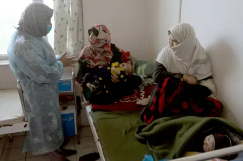 Two women with their children have to share one bed