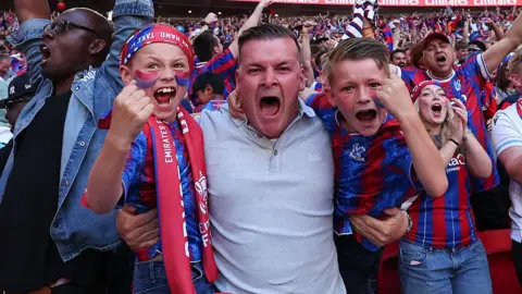 Getty Images A man with two young boys cheers into the camera.