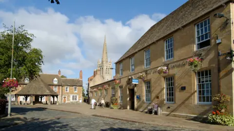 Getty Images Oakaham town centre, with a church in the background, cobbled street at the front of the photo and Post Office made from pale-coloured bricks on the right.