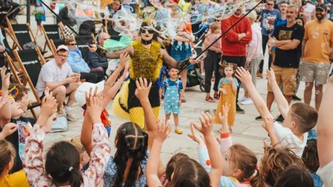 Giulia Spadafora ©️ Festival of Nature A person dressed as a bee creates bubbles for children as part of the Festival of Nature in Bristol