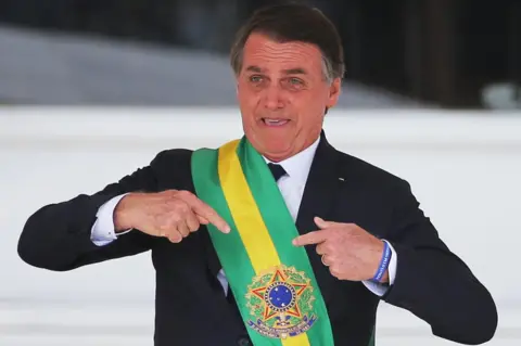 Reuters Jair Bolsonaro gestures after receiving the presidential sash from outgoing President Michel Temer at the Planalto Palace, in Brasilia, Brazil January 1, 2019