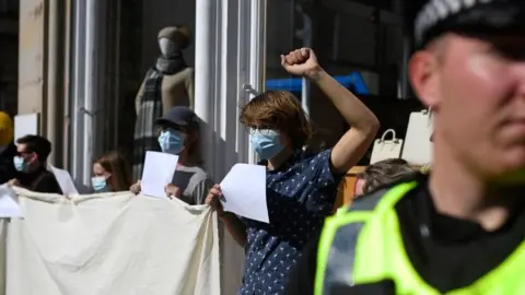 Getty Images People hold up blank placards to protest against arrests of protesters in Edinburgh