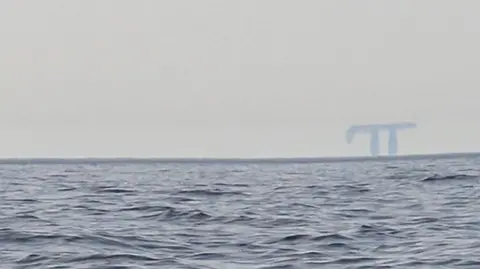 A picture of a Fata Morgana in the distance taken from a boat. 