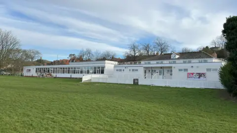 The picture shows the outside of Tor Sports and Leisure facility. The building is white in colour and there is grass in the foreground. 