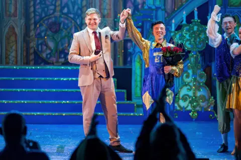 Christopher Bowen Lee Johnston and Lee Samuel raise arms and celebrate on stage
