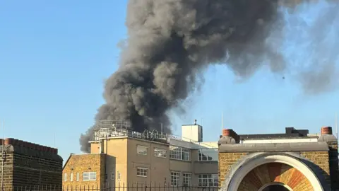 @alicecmoore/X Black smoke over buildings seen from Huntley Street, London.