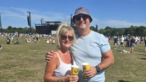 Shanice Miller A man and woman stand in a field in appears to be an outdoor concert