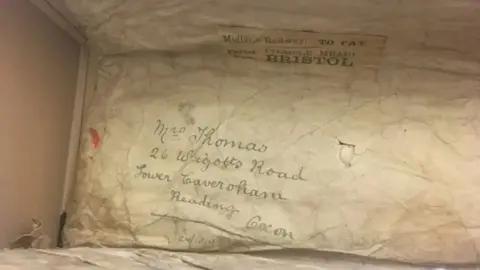 Thames Valley Police Museum An address written in flowing handwriting on an old crumpled piece of paper. The address is in Reading and the word Bristol can also be seen stamped on a label. 