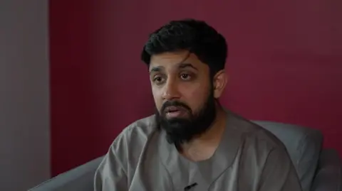 Hamzah Nanabawa being interviewed while sitting in a chair