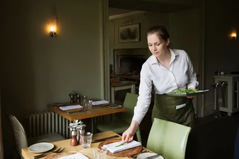 Woman wearing apron setting table in a restaurant