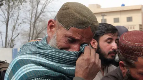 A man cries at a funeral for one of the victims