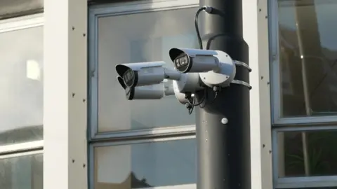 Three cameras are mounted on a street lamp 