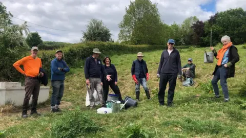 SVP A group of people pose for the camera in a line as they stand in a field near Stroud in Gloucestershire