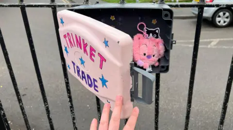 A hand opening a trinket trade box