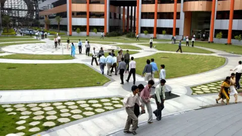 The The India Today Group via Getty Images A long line of tech workers at the sprawling Infosys campus in Bengaluru city.
