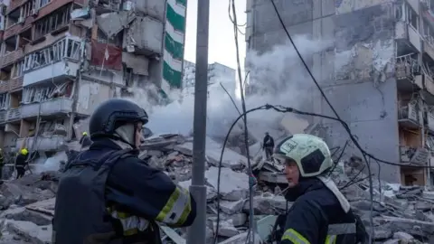 Ukrainian rescuers search for missing people at the site of a partially collapsed nine-storey residential building in Kyiv, following a Russian missile and drone attack. Photo: 14 May 2026