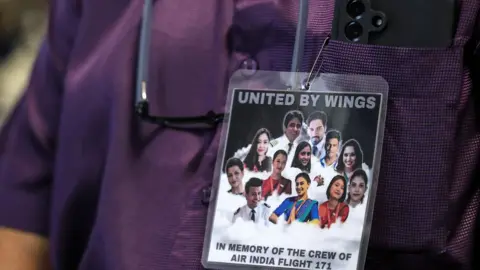 A man wears a badge with the portraits of the Air India flight crew members during a special prayer meeting in memory of the crew on the occasion of one-month anniversary of the Air India plane crash in Ahmedabad, at St Peter's Church in Mumbai, India, 12 July 2025. The Air India flight AI171, bound for London and carrying 242 people on board a Boeing 787-8 aircraft, crashed minutes after take-off in the Meghaninagar neighbourhood of Ahmedabad on 12 June.