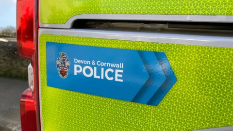The side of a neon yellow police van with the Devon & Cornwall Police logo and emblem.