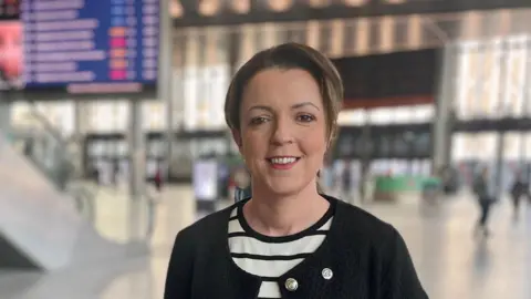 PA Media Liz Kimmins wearing a black jacket and a striped black and white top. She has brown short hair.