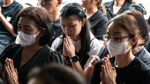 Mourners pray for the 12-year-old who died after being shot at the school outside Bangkok